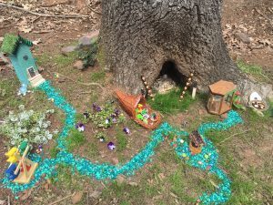 A Fairy village with farmer's market, bake shop, houses, wishing well and a turquoise sidewalk.